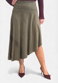 Gonna in camoscio verde oliva con orlo asimmetrico, design svasato e dettagli cuciti. Abbinata a décolleté in pelle verniciata color bordeaux.