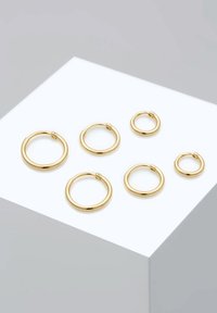 Set of six gold hoop earrings in various sizes, featuring smooth surface and secure clasps, arranged on a white display platform.