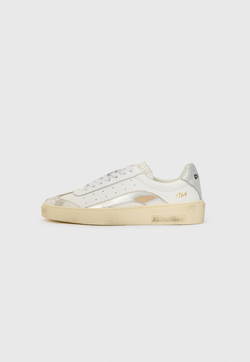 White leather sneaker with silver metallic accents, textured detail on the toe, and beige rubber sole. Features perforations and gold branding.
