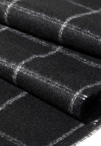 Czarna wełniana tkanina o miękkiej fakturze, z białym wzorem w kratkę i widocznym ściegiem. Rula materiału z czystym brzegiem.