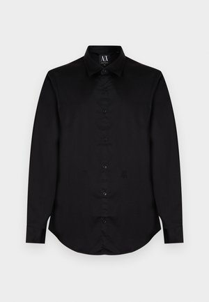 Chemise noire à manches longues avec boutons, col classique et logo A|X subtil sur le bas à gauche devant.