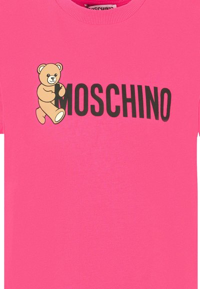T-shirt en coton rose avec un graphique d'ours à gauche et "MOSCHINO" écrit en lettres noires en gras sous le graphique.