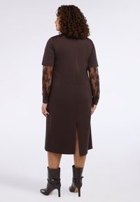 Brązowa sukienka midi z krótkimi rękawami i koronkowymi akcentami na rękawach. Tylny rozporek i gładka tekstura. Połączona z czarnymi, sięgającymi do kolan, na obcasie botkami.