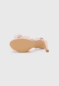 Blush satin high-heeled sandal with a thin ankle strap, ruffled tulle accent, and small pearl details. Light-colored sole with textured grip.