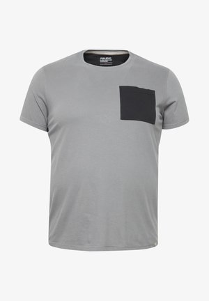 Szürke póló rövid ujjal, kerek nyakkal és fekete folt zsebbel a bal mellrészen. Puha, pamutszerű anyagból készült.