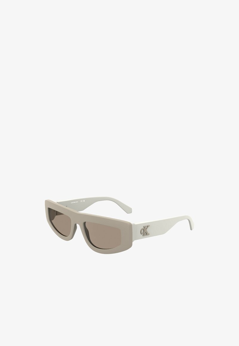 Sunglasses with a matte cream frame and brown tinted lenses. Features a rectangular design and a logo accent on the temple.