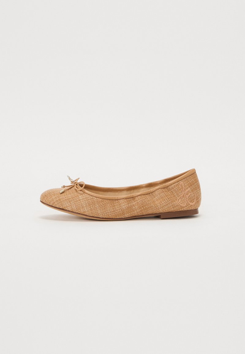 Ballet flat in light tan woven fabric with a rounded toe, decorative bow on the front, and subtle branding on the side; low-profile sole.