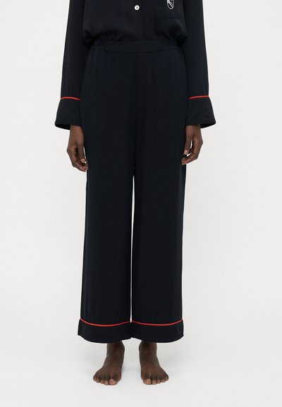 Pantaloni neri a gamba larga realizzati in tessuto morbido, con un accento rosso all'orlo. La vita è elastica per garantire comfort.