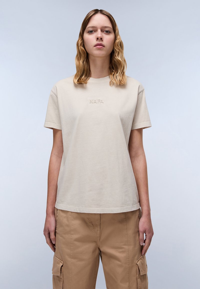 Beige katoenen t-shirt met korte mouwen en een ronde hals, met geborduurd "NAPA" in een subtiele tint, gecombineerd met losse kaki cargopants.