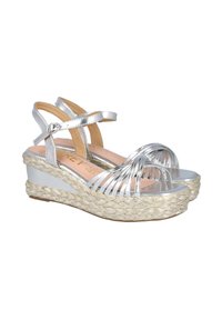 Sandalias de cuña plateadas con tiras, con una plataforma de yute trenzado; cuentan con un upper metálico brillante, punta cerrada y correa ajustable en el tobillo.