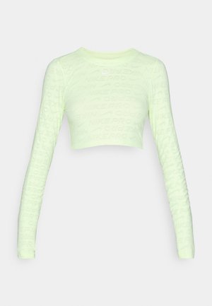 Gaiši zaļš garām piedurknēm īss tops ar visā virsmā redzamu "NIKE PRO" teksta rakstu. Pieguļošs, gluds audums, noapaļota kakla izgriezums un piegulošas piedurknes.