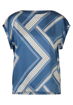 Woman wearing a blue and white geometric patterned short-sleeve top and matching flowing midi skirt with silver high-heeled sandals.