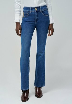 Jeans évasés en denim avec un lavage moyen. Présente un design classique à cinq poches, deux boutons et des accents en métal doré.