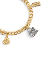 Bracciale in catena color oro con un charm a forma di cuore texturizzato in oro, un charm a forma di lucchetto in argento con dettagli decorativi e un'etichetta in oro contrassegnata "COACH."