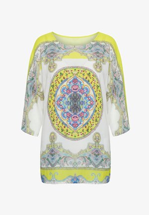 Biała i żółta bluzka z długim rękawem z misternymi kwiatowymi i geometrycznymi wzorami w kolorach niebieskim, różowym i zielonym na przodzie i rękawach.
