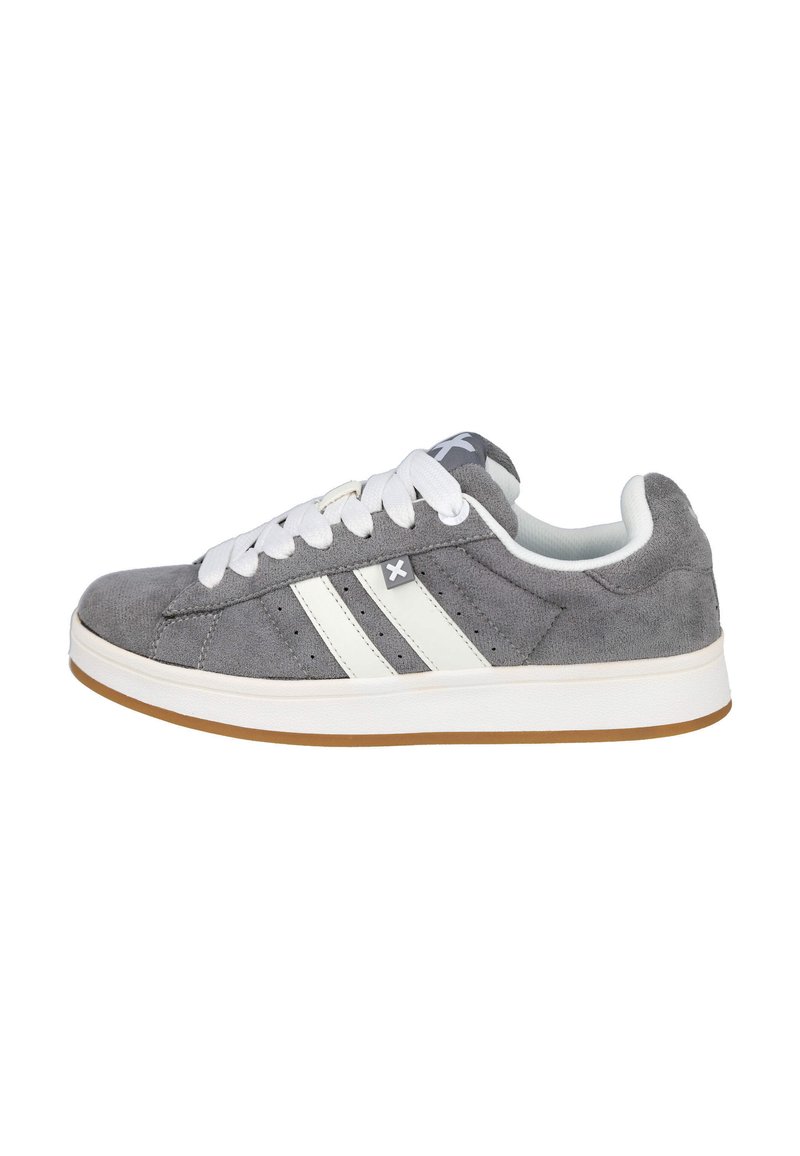 Zapatilla de ante gris con rayas blancas, cordones planos blancos y suela de goma. Presenta perforaciones para ventilación y un detalle del logo.