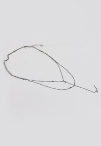 Srebrna warstwowa naszyjnik z łańcuszków o różnych ogniwach, okrągłymi koralikami oraz zapięciem na zatrzask.