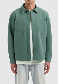 Groene button-up shirt van een stevige stof met twee voorke pockets, een klassieke kraag en een subtiele logodetail aan de linkerkant.