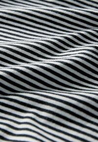 Tessuto a righe bianco e nero con una texture morbida. Le righe variano in larghezza e sono disposte orizzontalmente, creando un motivo ondulato.