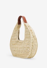 Bolso de paja tejido en color crema con forma curvada y un asa recortada, presenta un acento de cuero marrón en el borde del asa.