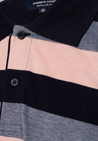 Gestreiftes Poloshirt in Marineblau, Pfirsich und Grau. Es verfügt über einen gerippten Kragen, eine Knopfleiste und einen strukturierten Stoff mit horizontalen Streifen.