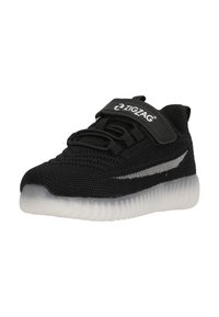 Scarpa sportiva nera con tomaia in mesh, lacci elastici e cinturino in Velcro. Presenta una suola in gomma traslucida e un accento argento sul lato.