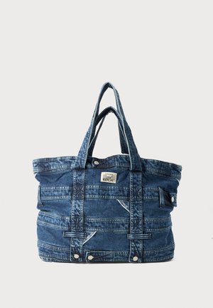 Denim draagtas met dubbele handvatten, uitgevoerd met een gestructureerde afwerking, gestikte patronen en een logo patch, in een donkerblauwe kleur.