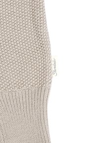 Beige knit fabric with a textured stitch pattern, featuring a small white label with "Sterntaler" stitched on the side.