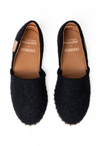 Czarne filcowe buty wsuwane z naturalną skórzaną wkładką, wyróżniające się teksturowaną powierzchnią i szytą jutową podeszwą. Źródło marki widoczne w środku.