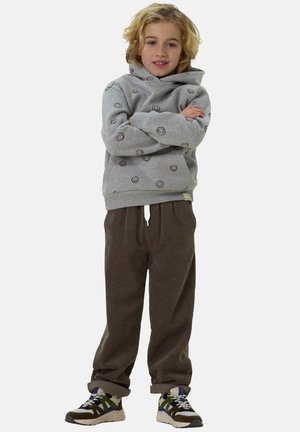 Grauer Kapuzenpullover mit einem Smiley-Gesicht-Muster, kombiniert mit braunen Cordhosen. Das Kind trägt mehrfarbige Sneakers.