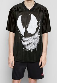 Black mesh short-sleeve shirt featuring a large white graphic design with a menacing face, paired with black shorts.