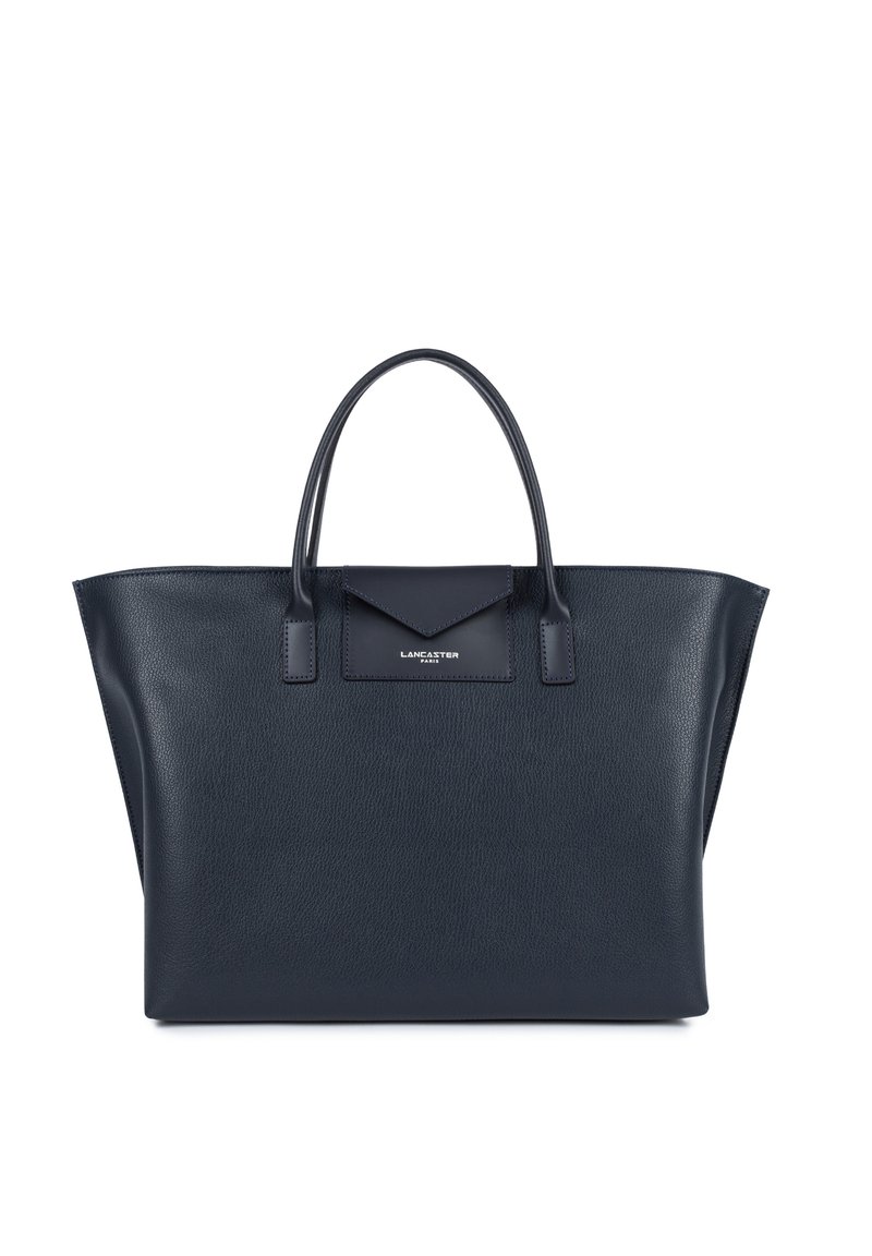 Sac fourre-tout en cuir bleu marine avec une forme structurée, deux poignées supérieures, et un accent en rabat portant un logo. Surface texturée avec un design minimaliste.