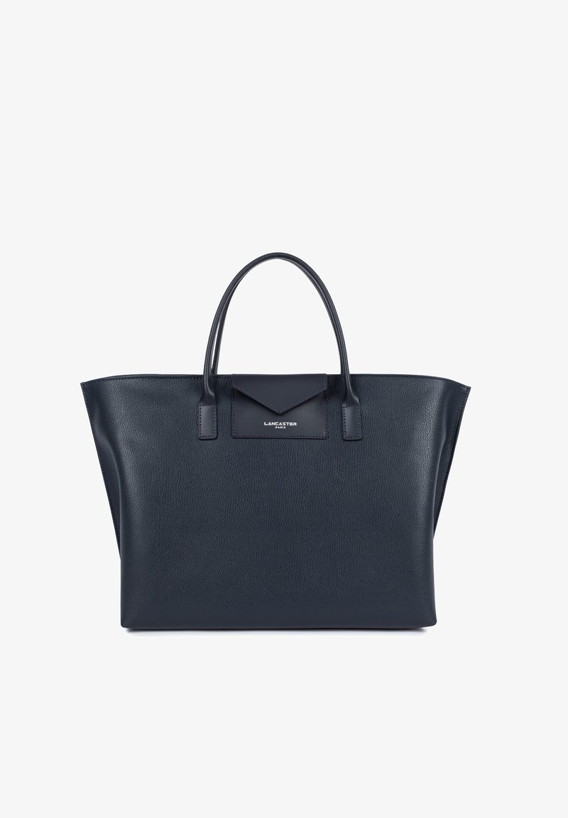 Sac fourre-tout en cuir bleu marine avec une forme structurée, deux poignées supérieures, et un accent en rabat portant un logo. Surface texturée avec un design minimaliste.
