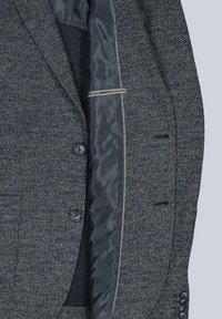Texturierter dunkelgrauer Blazer mit gemustertem Außenmaterial, kontrastierendem schwarzen Futter, Revers mit Kerbe und Zwei-Knopf-Verschluss.
