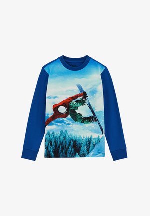 Dug džemper dugih rukava plave boje s grafikom snowboardera u crvenoj i zelenoj, postavljen protiv snježne planinske pozadine s borovima.