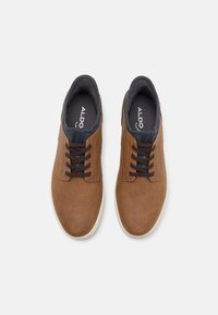 Brown leather lace-up shoes with a smooth texture, padded navy blue collar, and light rubber sole. Features contrasting brown laces.