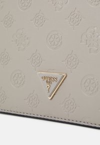 Grå syntetisk håndtaske med et prægning mønster og et trekantet guldhardware-logo. Glat tekstur med dekorativ syning.