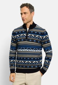 Marineblauer, gemusterter Strickpullover mit halbem Reißverschluss und gerippten Bündchen, der geometrische und abstrahierte Designs in kontrastierenden Farben aufweist.