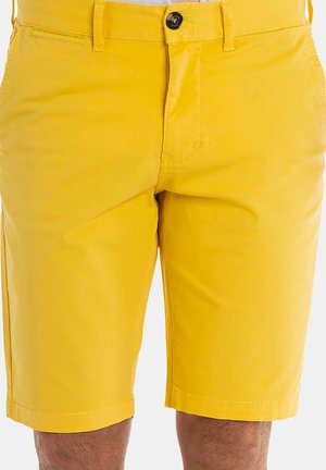 Shorts jaunes en tissu léger. Ils disposent d'une fermeture à bouton, de poches avant et d'un design à l'avant plat avec un ourlet net.