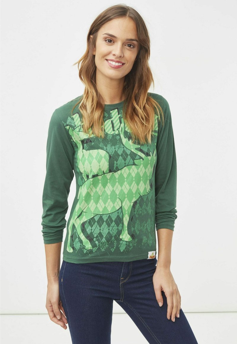 Camiseta verde de manga larga con un patrón de argyle que presenta gráficos de animales. Hecha de material suave, combinada con unos jeans de color azul oscuro.