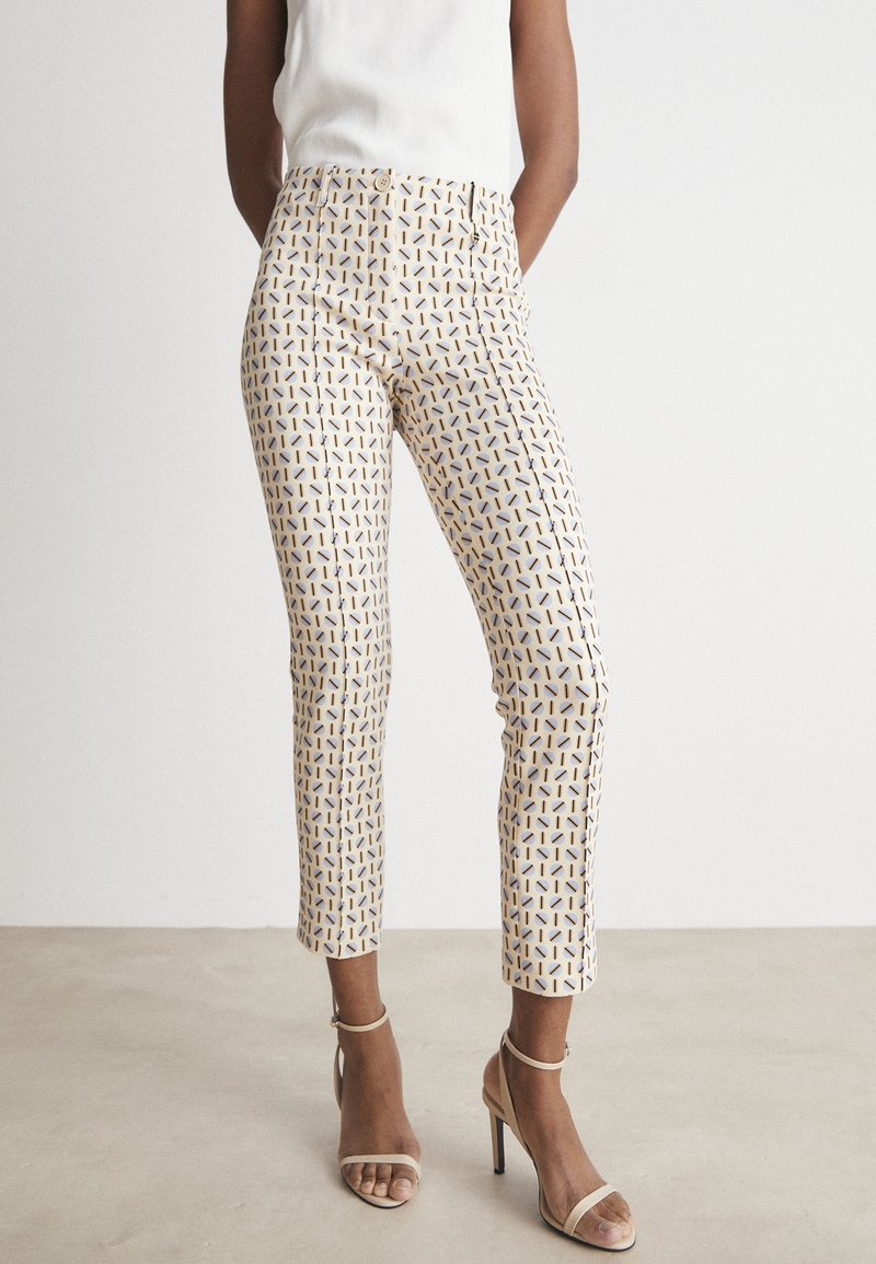 Hvide bukser med et geometrisk mønster i gul og marineblå. Lavet af letvægtsstof, med en lige pasform og ankellængde.