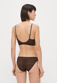 Sutiã marrom e cuecas combinando feitas de um tecido texturizado com um padrão sutil. Alças ajustáveis e fecho de encaixe nas costas do sutiã.