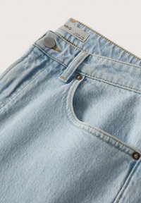 Jeans de mezclilla azul claro con un corte clásico, que presentan un bolsillo frontal y un botón de metal. La tela tiene una textura suave y un desvanecido sutil.