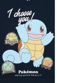 Tengerészkék póló, amelyen egy nagy világoskék Squirtle grafika található, valamint Pikachu, Bulbasaur és Charmander Pokémon jelvények. A felirat: "Téged választalak!"