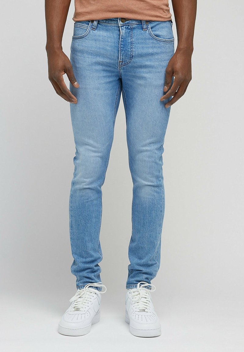 Jeans slim-fit azzurri chiari in denim, con un classico design a cinque tasche e un leggero effetto sbiadito. Abbinati a sneaker bianche.