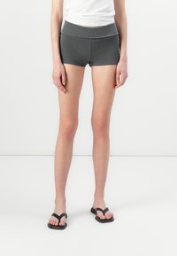 Grå ribbede shorts med en bred linning, som har en figursydde design. Brukt med svarte flip-flops, og viser et enkelt, uformelt utseende.