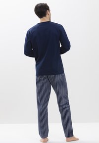 Camiseta de manga larga en color marino combinada con pantalones de pijama a rayas azules y blancas, que presentan un corte holgado y un tejido suave.