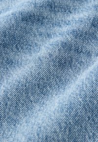 Lichtblau denimstof met een licht gestructureerd oppervlak en een fijne weving, met subtiele variaties en een vaag patroon.