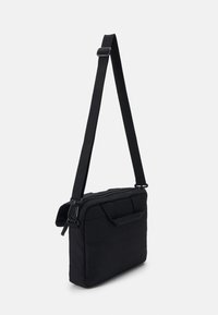 Svart tygmessengerbag med avtagbar axelrem, dragkedjestängning, framficka och ett huvudfack; rektangulär form.