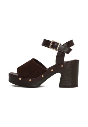 Dark brown open-toe sandal with chunky heel, ankle strap with gold buckle, and gold studs along the sole edge.